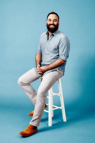 Bryan DeLuca, co-founder of FlightPlan Ventures, seated on a stool against a blue background